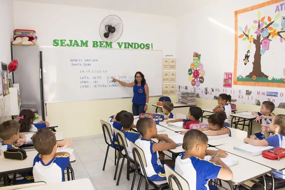 Professora ministrando aula com turma atenta no Colégio Barcelos